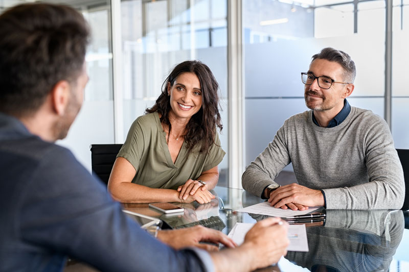 a younger couple speaking with a retirement planning consultant