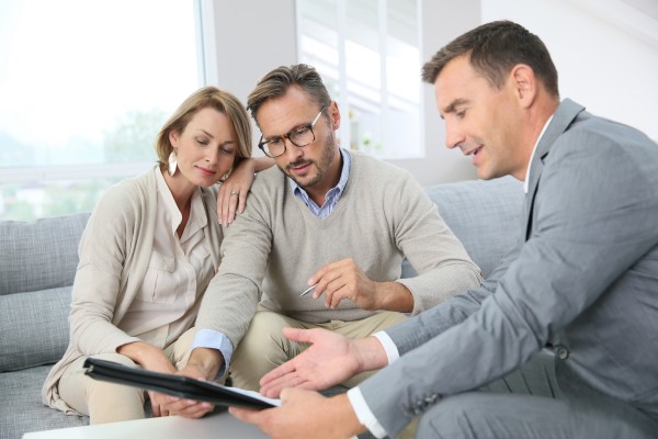a middle aged couple discussing their financial goals with their estate planning advisor