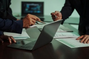 business professionals closely review a balance sheet and digital Global Investment Portfolio data