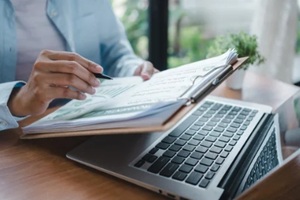 ESG report corporate compliance reporting concept close up hands typing on laptop keyboard and holding environmental sustainability document for business governance data entry