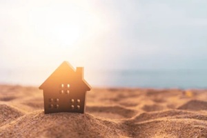 small home model on sunset beach sand texture background